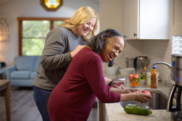 Two women washing fruits and vegetables in the kitchen sink