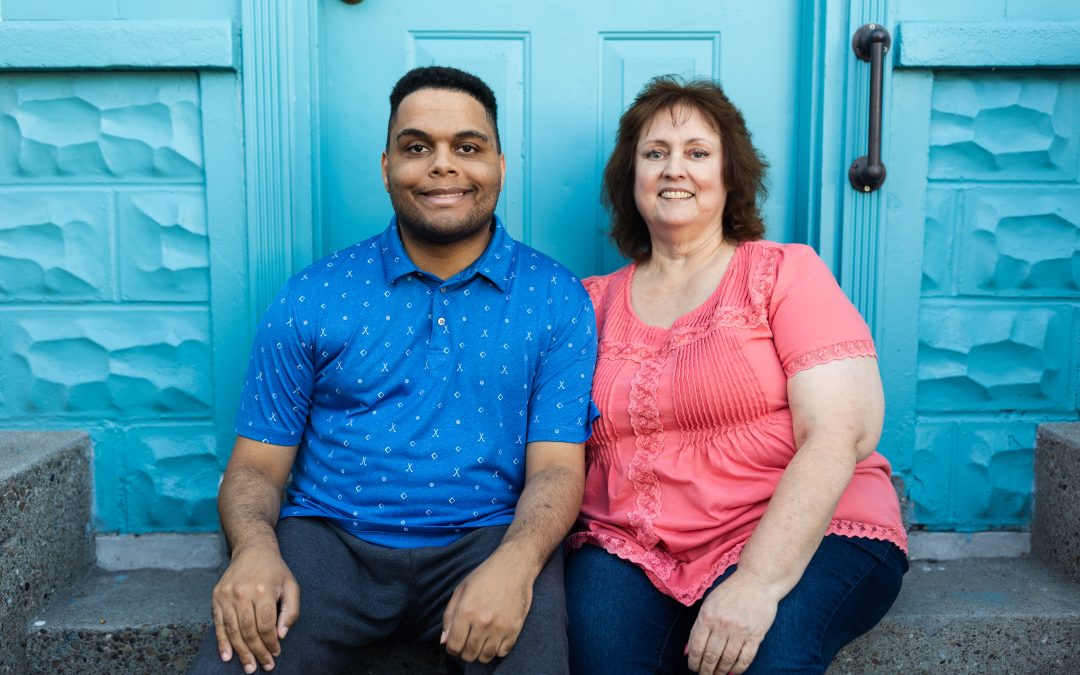 Elijah and his mom, Aleta, sitting in front of a blue building