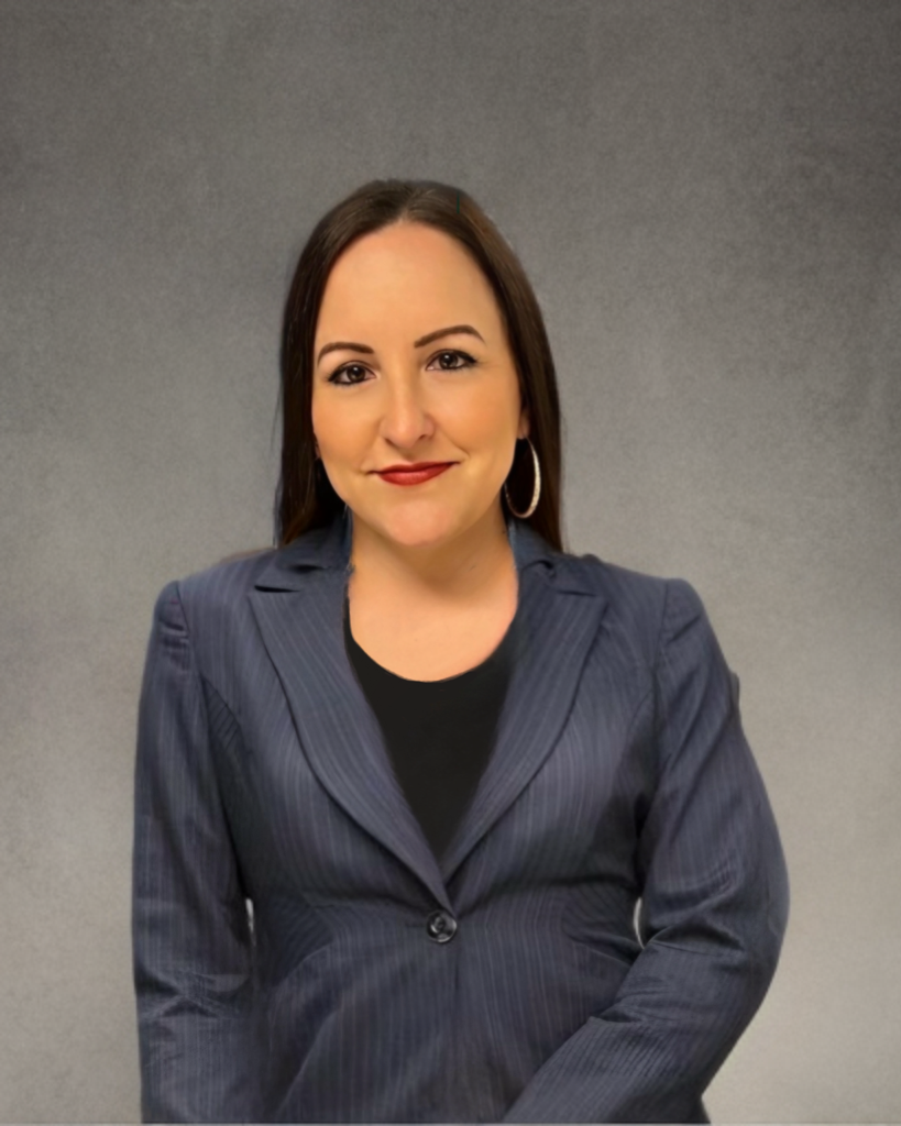 Tracy sitting for a headshot in a blazer and big hoop earrings