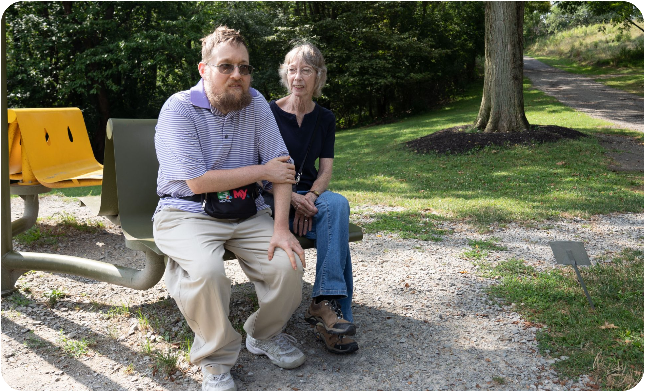 Elderly man and woman sitting on a park bench.