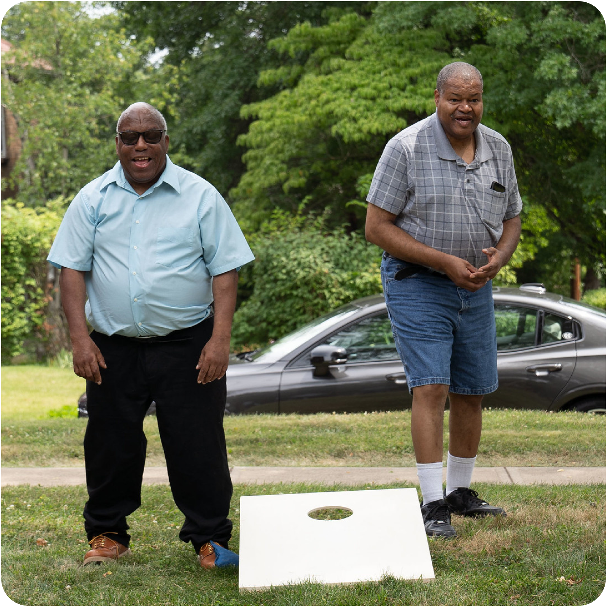 Two men playing cornhole at an outdoor event