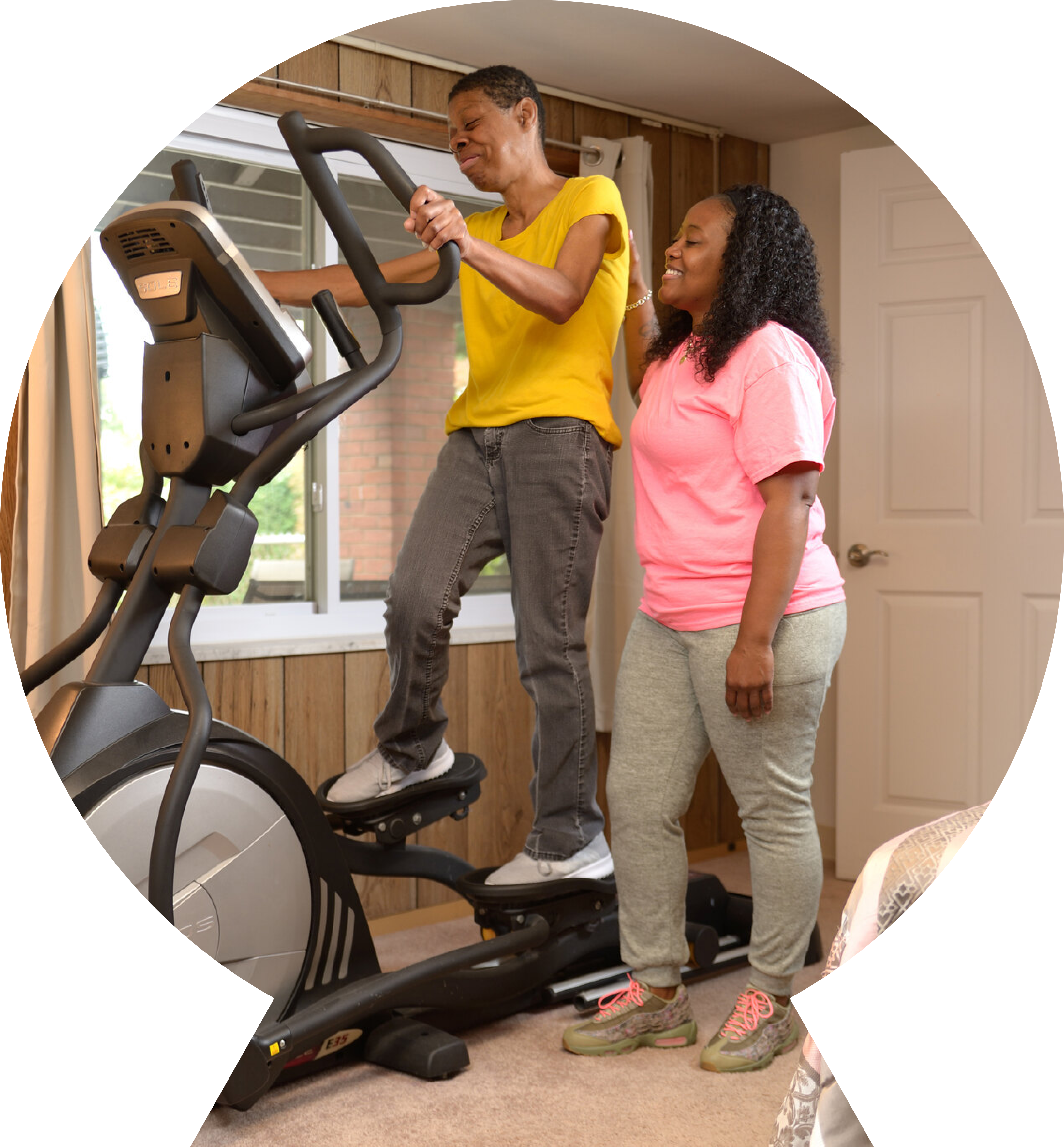 A woman working out on an elliptical with assistance.  