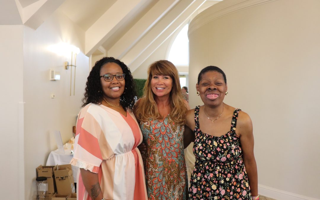 Three women smile for the camera at an event.