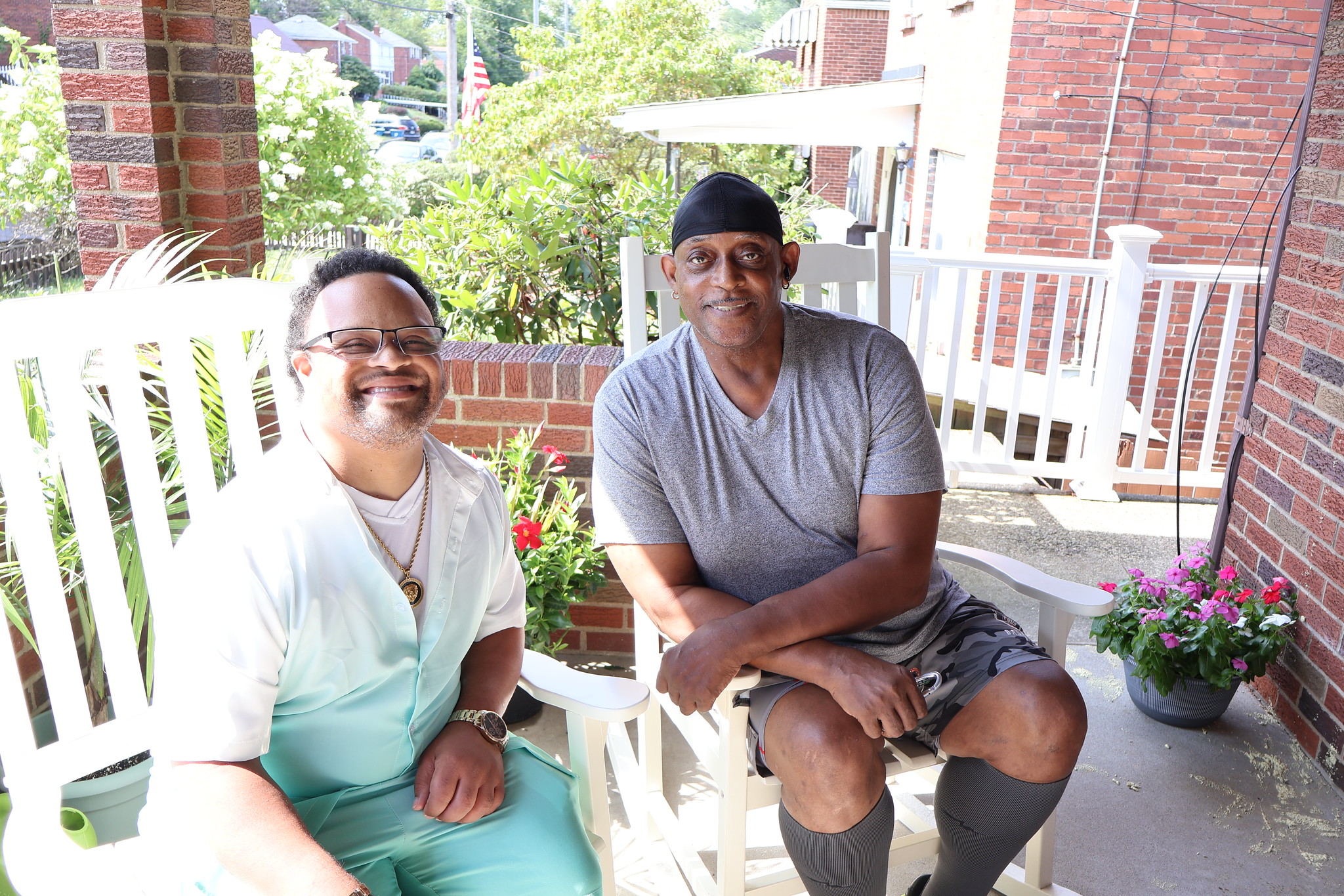 Parriz and David sitting on a front porch smiling on a beautiful day