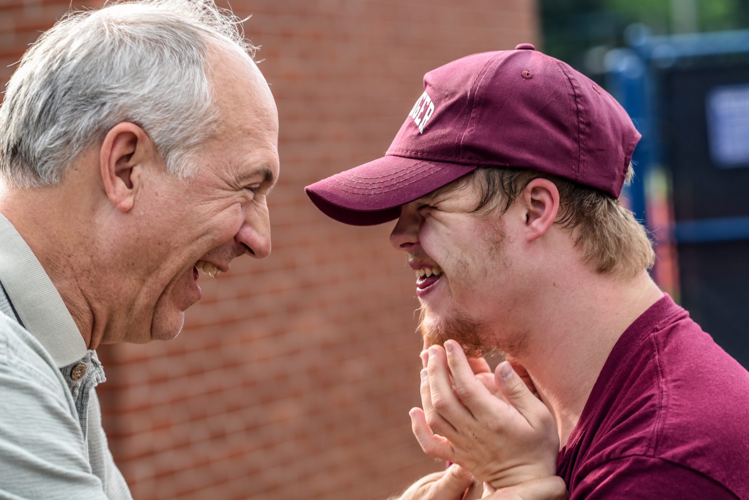 Older and younger man smile at one another