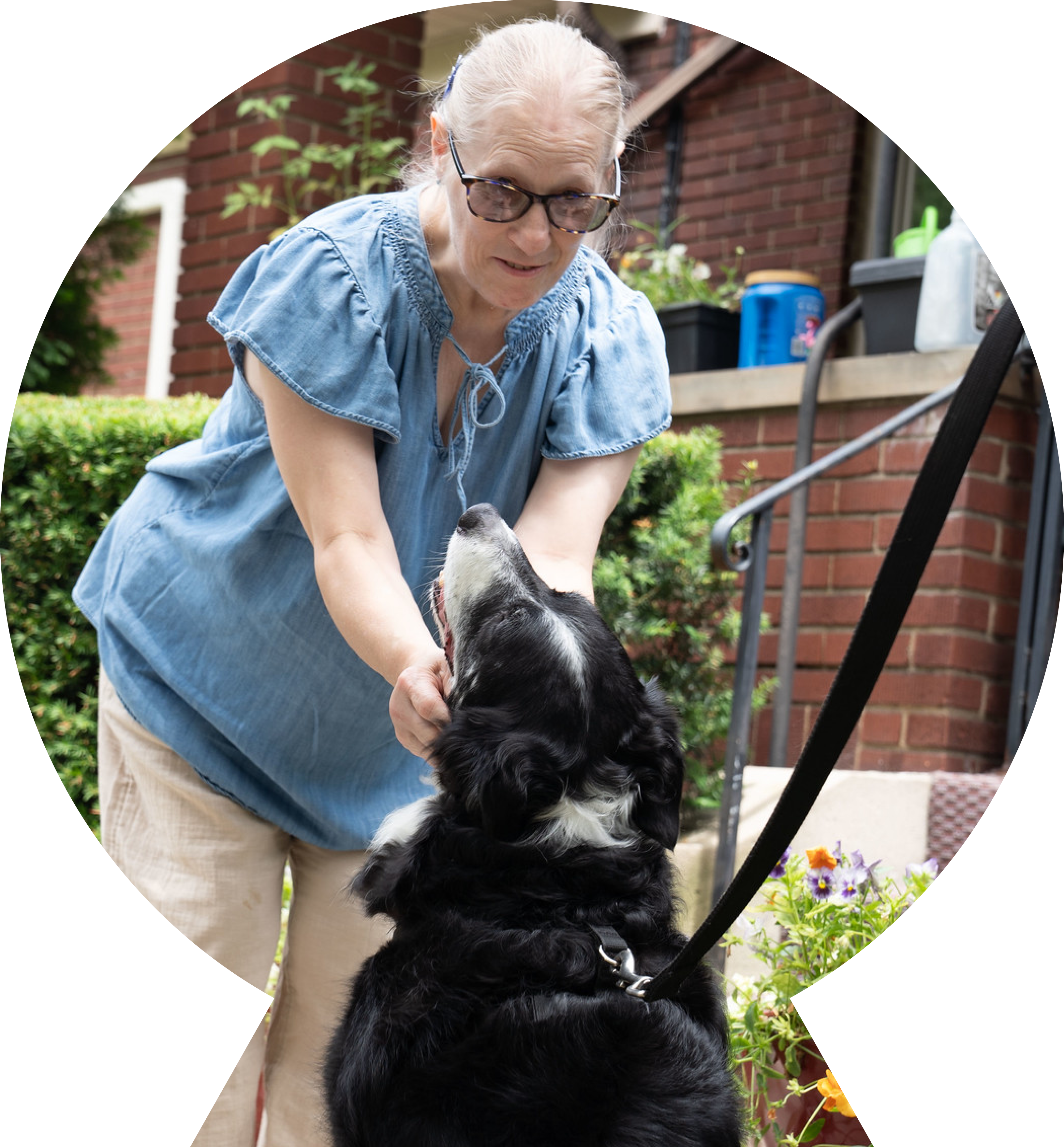 Older woman petting a black dog. 