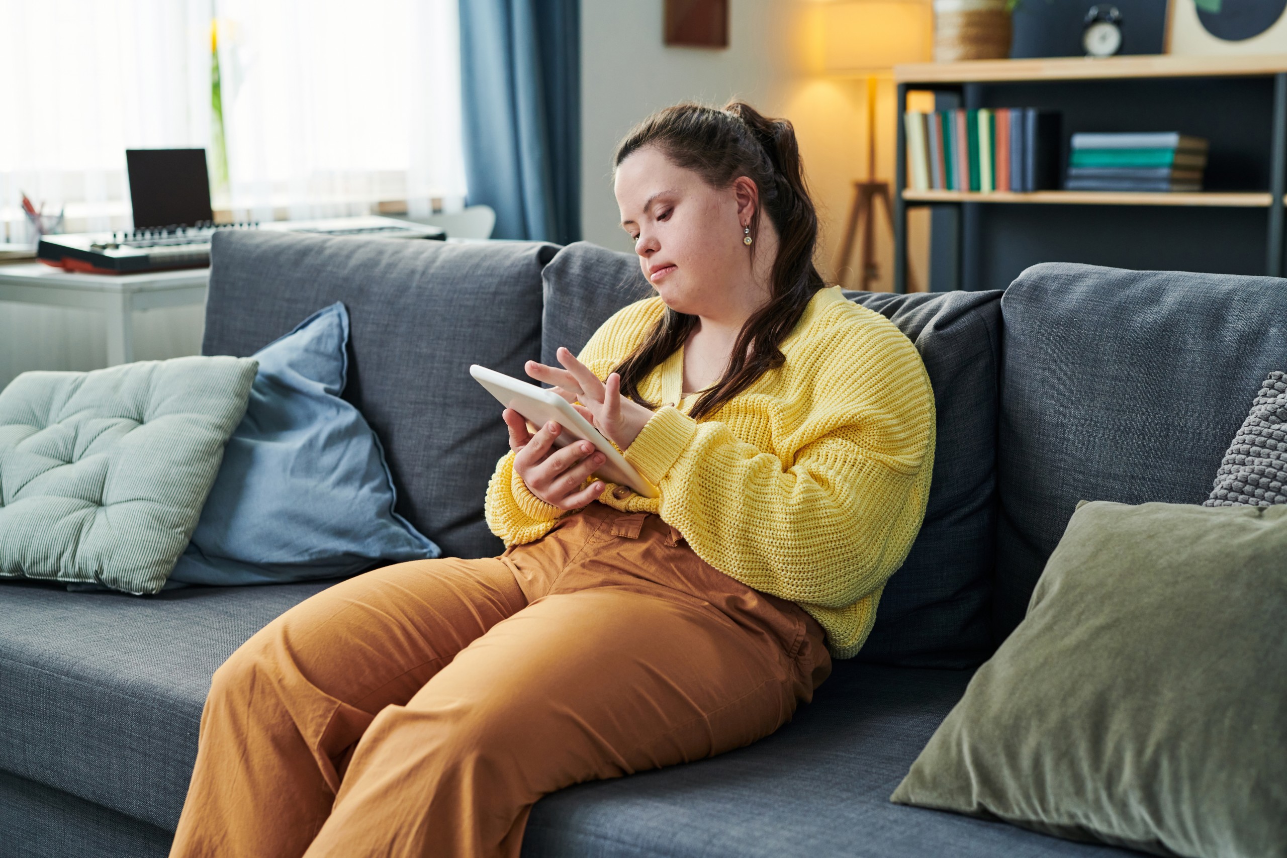 Woman sitting on couch using iPad.