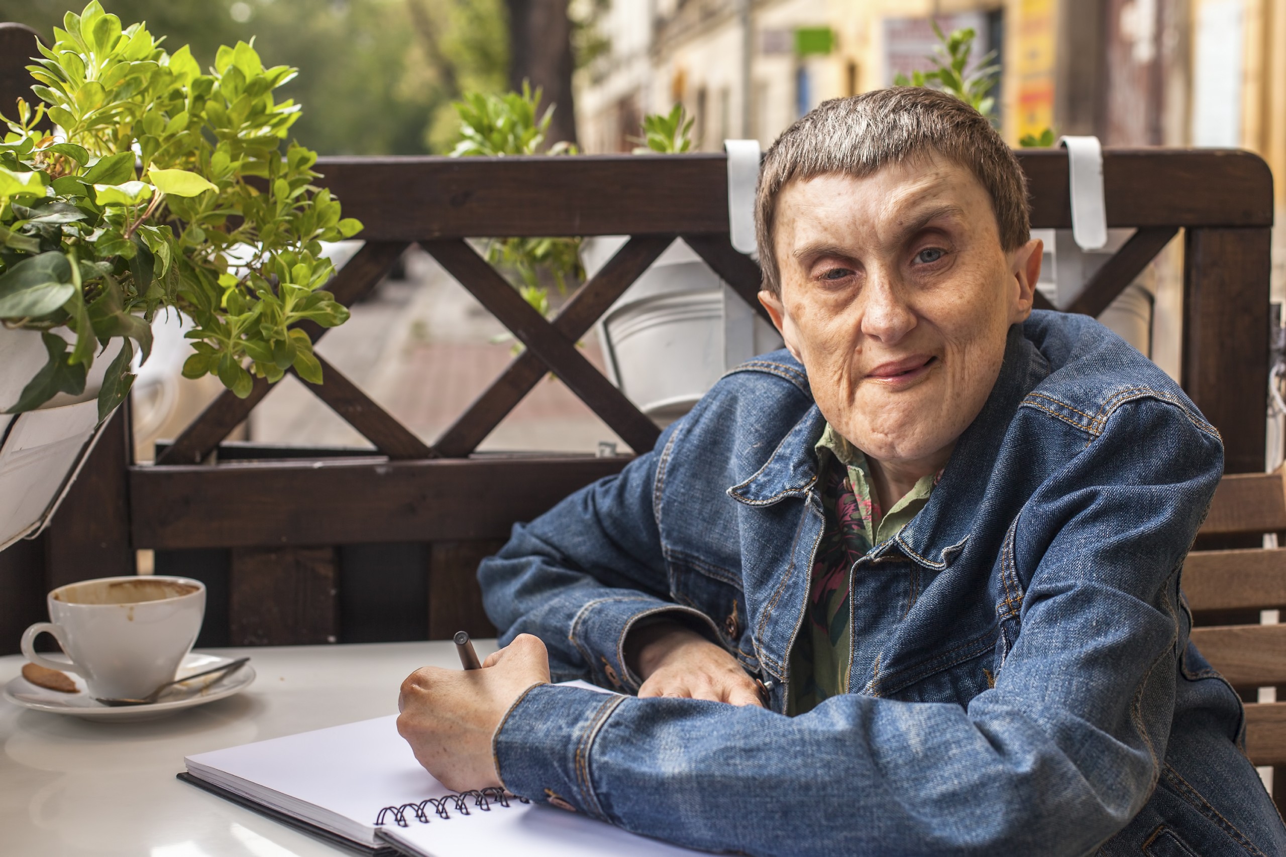 Older person sitting on her terrace and writing in notebook.